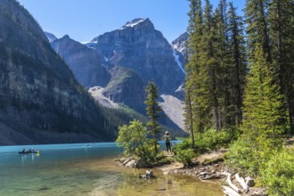 Tourists are canoeing on the turquoise, glacier fed moraine lake with its surrounding mountains and