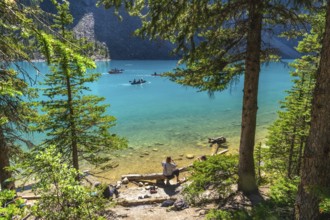 Tourists canoeing on the turquoise waters of moraine lake, surrounded by rocky mountains and lush