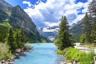 Turquoise water flowing into the stunning lake louise in banff national park, with tourists