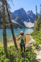Female tourist admiring the turquoise waters of moraine lake with the valley of the ten peaks in