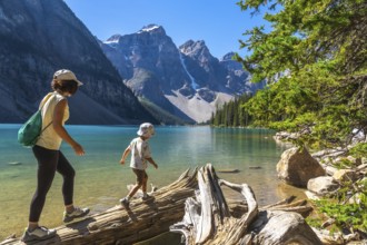 Mother and son enjoying a leisurely walk on a weathered log along the scenic shores of moraine