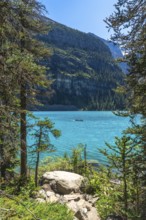 Tourists are canoeing on the turquoise, glacier fed moraine lake with the scenic valley of the ten