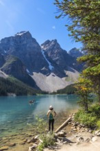 Female tourist standing on the shore of pristine turquoise moraine lake, admiring the majestic