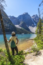 Female tourist with backpack enjoying the breathtaking view of moraine lake and the valley of the