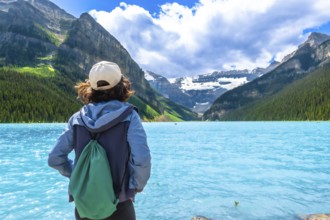 Female tourist admiring stunning turquoise waters of lake louise, framed by victoria glacier and