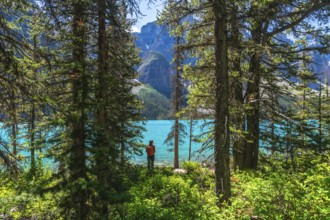 Tourist with a backpack enjoying the breathtaking view of turquoise moraine lake, surrounded by