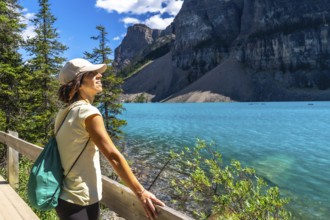 Female tourist admiring the turquoise waters of moraine lake, with the stunning valley of the ten