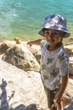 Young tourist pointing at a golden mantled ground squirrel on a rock by the turquoise waters of