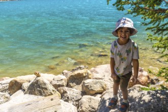 Happy child wearing a bucket hat standing by the turquoise water of moraine lake with a chipmunk