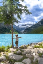 Young tourist with arms outstretched, enjoying the stunning turquoise waters of lake louise and the