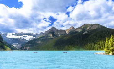 Canoeing on the turquoise waters of lake louise, tourists enjoy a breathtaking summer landscape