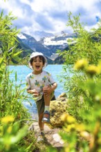 Young child having fun by the turquoise waters of lake louise with the majestic rocky mountains in