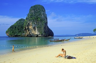 Rocks in the sea, people and longtail boats on Pranang Cave beach, two years in front of the