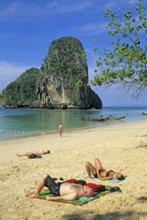 Rocks in the sea, people and longtail boats on Pranang Cave beach, two years in front of the