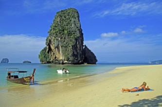 Rocks in the sea, people and longtail boat on Pranang Cave beach, two years in front of the