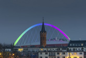 Evening view of residential buildings on the banks of the Rhine, behind them the church tower of St