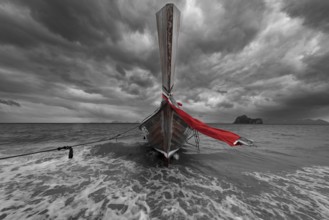 Longtail boat on the beach with dark rain clouds behind it, Koh Ngai island, Andaman Sea, Satun