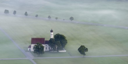 St. Coloman pilgrimage church in front of sunrise in autumn fog, Königswinkel, Ostallgäu, Allgäu,