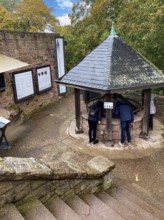 Tourists look down into a covered well shaft of 176 meters deep deepest castle well in the world