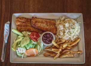 Plate of fried fish fillet with salad and french fries on wooden table, Top view of delicious fried