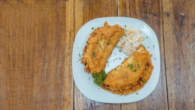 Enchilada with salad served in a plate on a wooden table, View of two enchiladas with salad served