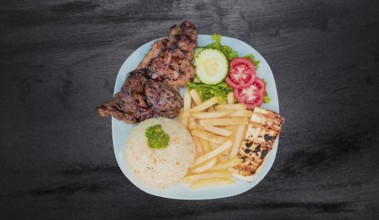 Plate of roasted chicken with rice and french fries on wooden table, Top view of plate of roasted