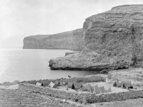 Military tents at walled campsite overlooking sea cliffs at Xlendi Bay, Island of Gozo, Malta,