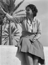 Portrait of middle aged woman sitting on wall, wearing smart casual clothing, Malta, Europe, 1956