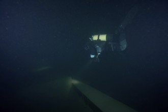 Diver examines a lediwreck, wreck of a lediship, ledi ship, cargo ship for mass freight, bulk