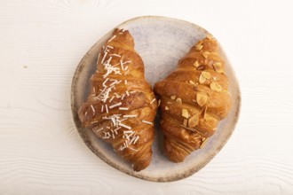 Croissant on blue plate on white wooden background, top view, flat lay, close up