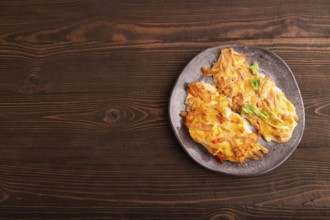 Baked chicken meat with cheese and tomatoes on brown wooden background. top view, flat lay, copy