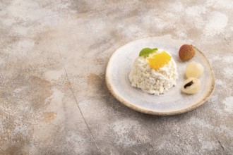 White ?ottage cheese, Curd, with orange and lychee on brown concrete background, side view, copy