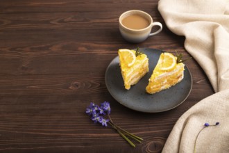Lemon cake on brown wooden background and linen textile, cup of coffee, side view, copy space