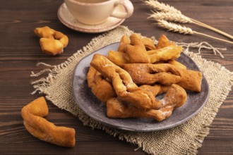 Crunchy biscuit Brushwood cookies sprinkled with powdered sugar on brown wooden background and