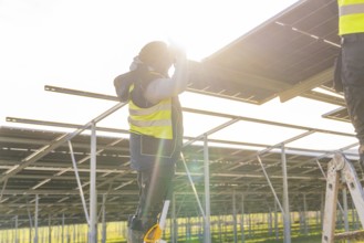 Person mounts solar panel on frame, bright sun in background, Energiewende, construction of PV open