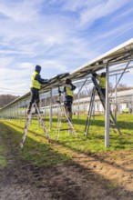 Workers install solar system in fields with ladders and safety equipment, Energiewende,