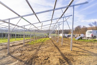 Unfinished solar system in open area with vehicles and building materials, energy transition,