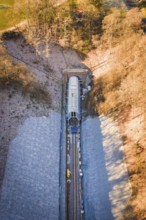 Railway line under a bridge through an autumnal forest, taken from the air, construction of the