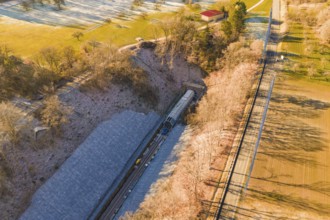 Drone view of a railway line through an autumn landscape with meadows and forests, construction of