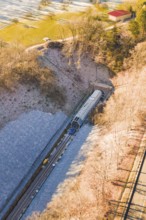 A Train Emerges from a Tunnel Surrounded by Forested Hills in a Wintry Setting, Construction of the