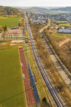 Railway line and road next to a sports field in a rural area, construction of the Hermann Hesse