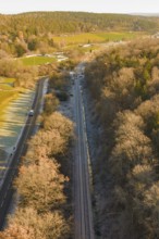 Railway line between trees and a country road in an autumn landscape, construction of the Hermann