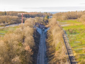 Aerial view of a railway tunnel surrounded by trees and meadows in autumn, construction of the