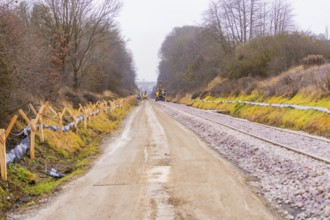 Landscape view of a road next to tracks with construction work and winter trees, construction of