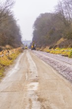 A long way next to a construction site on the tracks surrounded by winter trees, construction of