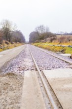 Railway tracks run in perspective through a cloudy landscape, construction of the Hermann Hesse