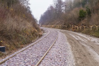Curvy train tracks run through a quiet, wooded landscape with gravel, built by the Hermann Hesse