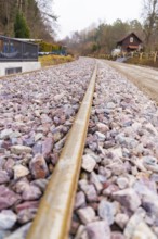 Railway tracks lead past a house through a rural, cloudy landscape, built by the Hermann Hesse