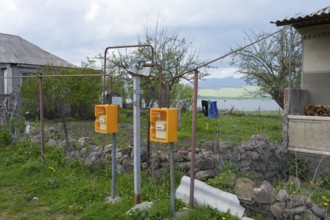 Two yellow gas meters next to a fence overlooking a lake and rural area, Sameba, Kvemo Kartli