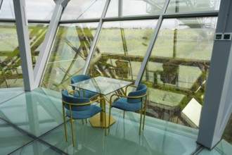A stylish interior with glass floor and modern blue chairs offers an open view, Diamond Bridge,